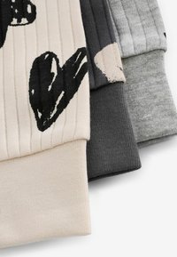 Tre maniche in tessuto a costine di colore beige, grigio scuro e grigio chiaro. Una manica presenta un motivo astratto nero su fondo beige. Materiale in maglia texturizzata.