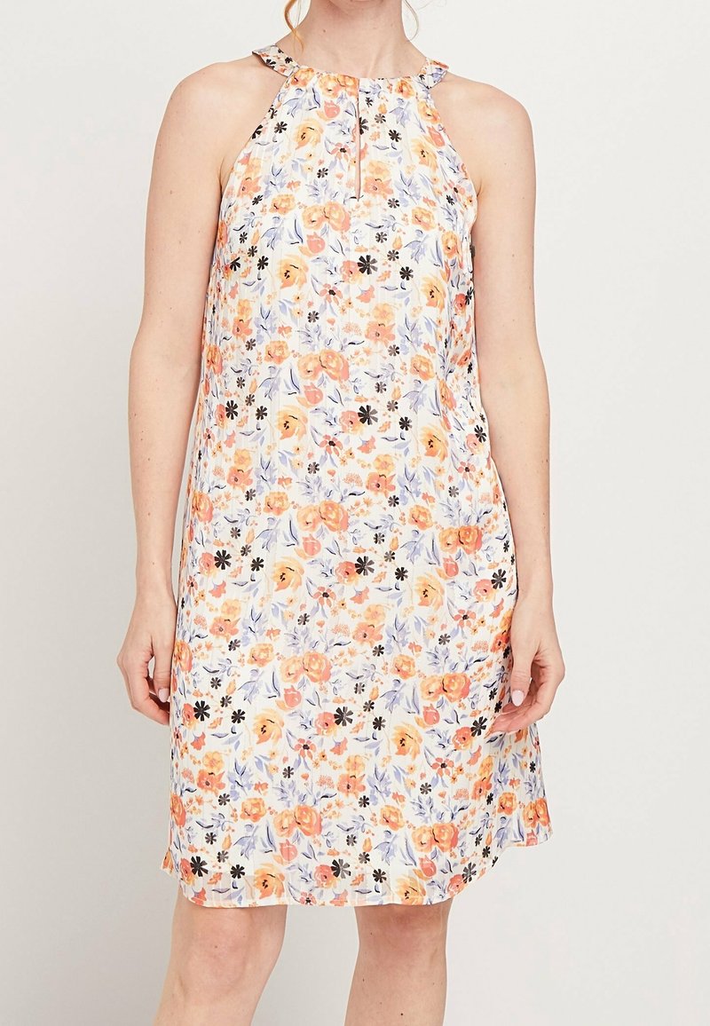 Robe sans manches arrivant au genou avec un col halter et un motif floral aux tons orange, noir et violet sur un tissu blanc.
