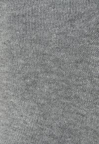 Tissu en tricot gris avec une texture fine et côtelée. Le matériau semble doux, avec une couleur uniforme et des variations subtiles d'ombre.