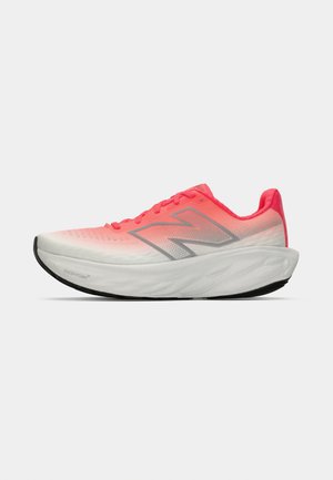 Vaaleanharmaa ja neonpinkin sävyinen New Balance -juoksukenkä, jossa on paksu vaimennettu pohja ja heijastava "N"-logo sivussa, esiteltynä sivuprofiilissa.