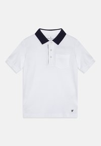 Hvid polo-shirt med en marineblå krave, udstyret med tre knapper, en brystlomme og en diskret logo-accent på sømmen. Glat stoftekstur.