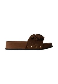 Sandale mule marron avec semelle plateforme en bois, décorée de clous dorés et d’un pompon à franges sur la bride.