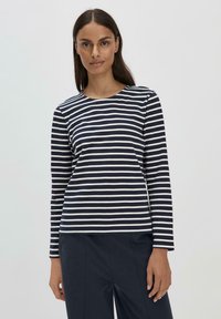 Gestreiftes Langarmshirt in Marineblau und Weiß mit rundem Halsausschnitt, aus glatt gewebter Baumwolle, kombiniert mit dunklen Hosen.