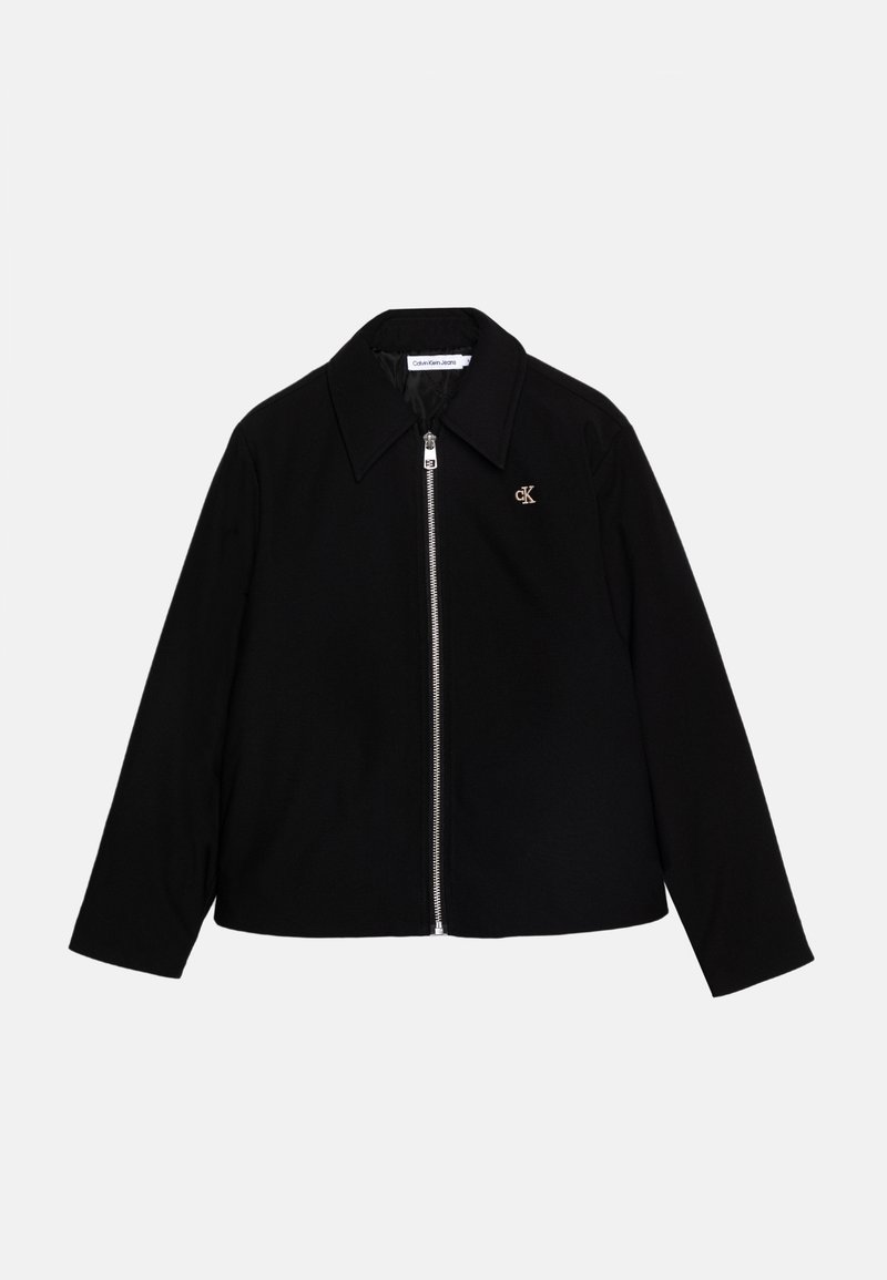 Giacca nera con zip e colletto ampio, realizzata in materiale liscio, con un piccolo logo dorato sul lato sinistro del petto e maniche lunghe.