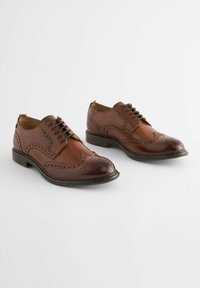 Chaussures brogue en cuir marron avec une finition polie, des perforations décoratives et un design classique à lacets avec un bout rond.