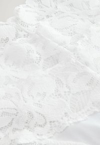 White lace fabric featuring a floral pattern with intricate details and a soft, textured surface, layered over a smooth background.
