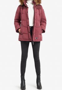 Chaqueta acolchada color granate con capucha desmontable forrada de piel, diseño acolchado, acentos negros, bolsillos laterales y detalle de logo en el dobladillo.