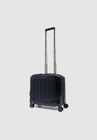Hartschalenkoffer in Dunkelblau mit vertikalen Rillen, einem ausziehbaren Griff und vier Rollen, die eine einfache Manövrierbarkeit ermöglichen.