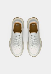 Λευκά δερμάτινα αθλητικά παπούτσια με ανοιχτογκρι λεπτομέρειες, στρογγυλή μύτη, διακριτικές διατρήσεις και λαστιχένια σόλα. Φέρουν σήμανση στην γλώσσα του παπουτσιού.