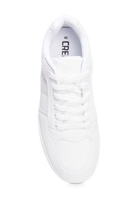 Zapatilla blanca hecha de cuero suave con punta redondeada, cordones planos y detalles perforados en los laterales. Etiqueta de tamaño visible en el interior.