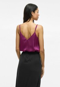 Magenta satino kamšalu su reguliuojamomis petnešėlėmis ir V formos nugarėle, derinamas su juoda aukštu liemeniu sijonu. Glaudžios tekstūros, elegantiška siluetas.