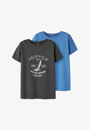 Dwie koszulki z krótkim rękawem i okrągłym dekoltem, jedna czarna z białą grafiką żeglarską i napisem, druga gładka niebieska, wyświetlone nachodzące na siebie.