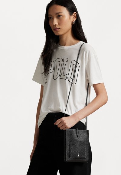 Μαύρη δερμάτινη τσάντα χιαστί με ανάγλυφη υφή, με μία μπροστινή τσέπη και αποσπώμενο λουρί ώμου, που διαθέτει μια μικρή λεπτομέρεια λογότυπου στο κάτω μέρος.