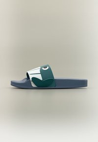 Μπλε σαγιονάρα με ευρεία λωρίδα που διαθέτει ένα σχεδιασμό βατράχου σε άσπρο και πράσινο, πάνω σε μονόχρωμο μπεζ φόντο.