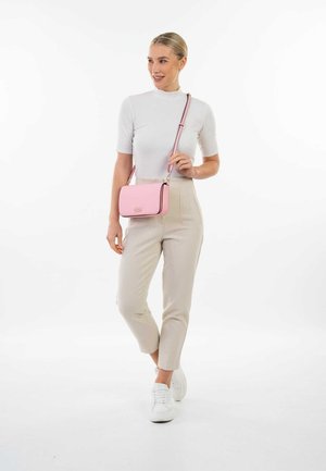 Sac bandoulière rose avec une texture lisse, des finitions dorées et des bordures noires. Forme rectangulaire mince avec une sangle réglable.