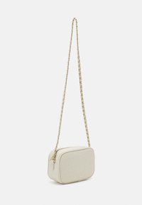 Vit läder crossover-väska med präglad logotyp, rektangulär form, guld kedjeslinga och dragkedjestängning. Texturerad yta och minimalistisk design.