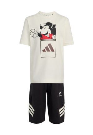 Chemise blanche à manches courtes avec un graphisme de Mickey Mouse et le logo Adidas, associée à un short noir avec les bandes et le logo Adidas.