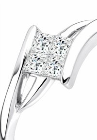 Sudraba gredzens ar gludu, pulētu apdari, kurā ir kvadrātveida klasteris no četriem caurspīdīgiem, princeses griezuma dārgakmeņiem, izstrādāts unikālā dizainā.