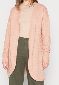 Ljusrosa stickad cardigan med ribbade ärmar och öppen front, med en strukturerad mönstring. Sammanställd med en beige topp och olivgröna byxor.