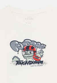 Cartoon-Dinosaur trägt einen rot-schwarzen Football-Helm und hält einen Football, mit dem Text "Football Touchdown Let's Play" auf einem weißen Shirt.
