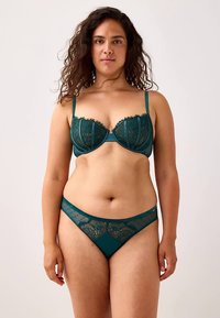 Teal lace lingerie set featuring a structured underwire bra and matching thong, detailed with floral patterns and sheer mesh accents.