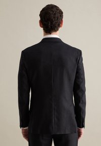 Chaqueta de traje negra con textura, con una abertura en la parte posterior, solapas tipo muesca y un corte ajustado. Presenta botones en los puños y un forro interior liso.