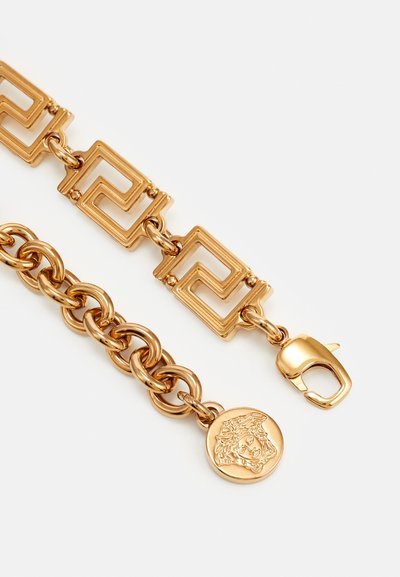 Armband in Goldton mit sich miteinander verbindenden geometrischen Gliedern, einem strukturierten runden Anhänger mit Motiv und einem sicheren Karabinerverschluss.