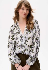 Blumenbluse mit tiefem V-Ausschnitt und Spitzenbesatz. Verfügt über lange Puffärmel, ein transparenter, leichter Stoff in Weiß, Grün und Lila.