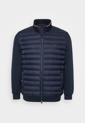 Marineblaue Steppjacke mit gesteppter Vorderseite, glatten Ärmeln und hohem Kragen. Verfügt über einen Frontreißverschluss und ein Logodetail.