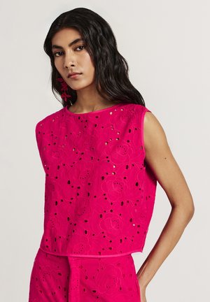 Haut sans manches fuchsia avec broderies florales et découpes, à la coupe décontractée et à la texture lisse.