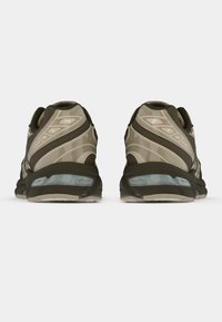 Sko med flerlagd beige og oliven overdel, med en teksturert design, polstret krage og gjennomskinnelige såler.