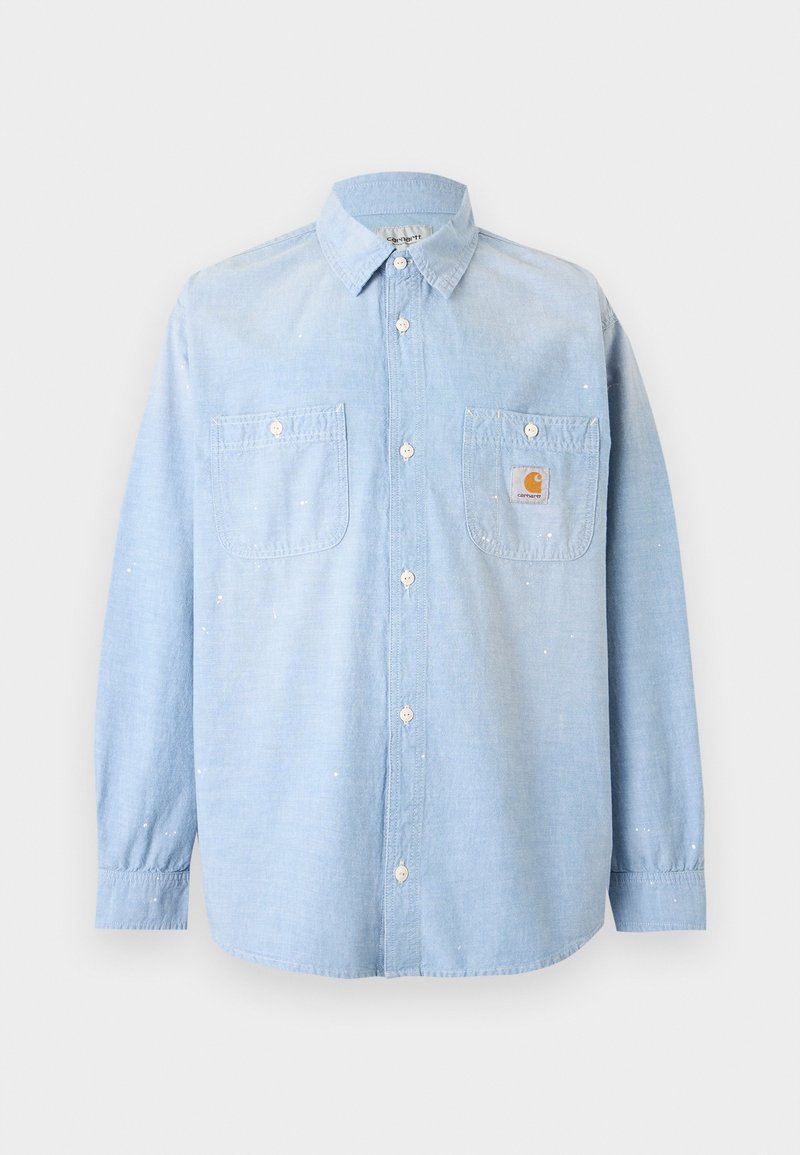 Camicia azzurro chiaro a maniche lunghe con bottoni, due tasche davanti, una con toppa con logo Carhartt e sottili dettagli di schizzi di vernice bianca.