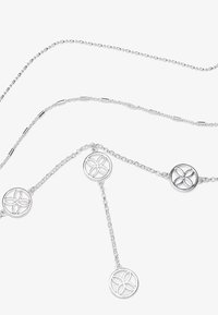 Silberne Halskette mit zarten Kettengliedern und drei kreisförmigen Anhängern, jeder mit einem durchbrochenen Blumendesign, das ein filigranes Muster zeigt.