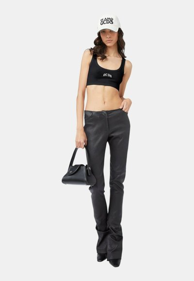 Cropped top nero con logo "GCDS", pantaloni in pelle neri a vita alta, borsa nera, cappellino bianco con testo "TI AMO GCDS", décolleté.