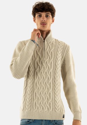 Crème kabelgebreide trui met een hoge kraag en een halve rits, met textuurpatronen en een geribbelde zoom en manchetten.