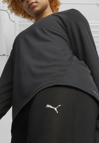 Czarny, długi rękaw sportowy top z teksturowanej tkaniny, w połączeniu z czarnymi legginsami z białym logo Puma. Slim fit z opuszczonymi ramionami.