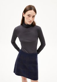 Langärmliges, eng anliegendes Rollkragenoberteil aus dunkelgrauem Stoff, kombiniert mit einem marineblauen Minirock mit einem strukturierten Karomuster.