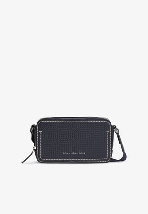 Obdĺžniková tmavomodrá kabelka cez rameno s textúrovaným povrchom, bielym prešívaním, zapínaním na zips a logom "Tommy Hilfiger" vpredu.