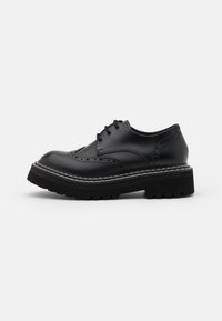 Chaussure en cuir noir à lacets avec des détails de brogue décoratifs, semelle épaisse noire et accents de couture blanche. Présente une texture lisse et une forme arrondie.