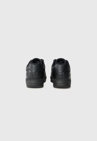 Baskets en cuir noir avec une texture lisse, bout rond et col rembourré. Présentent un profil bas et des détails de couture subtils.