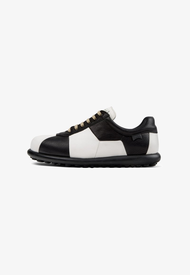 Leather sneakers with a black and white color block design, round toe, flat laces, and a black rubber sole featuring small nubs.
