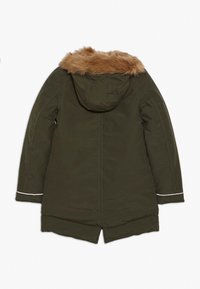 Cappotto invernale lungo di colore verde scuro, imbottito, con cappuccio attaccato rifinito in pelliccia sintetica marrone, cuciture visibili e polsini riflettenti, visto da dietro.