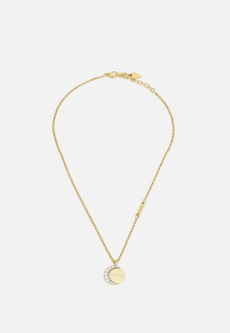 Collana in tonde oro con una delicata catena e un pendente circolare caratterizzato dalla scritta incisa "GUESS" e cristalli trasparenti lungo un bordo.