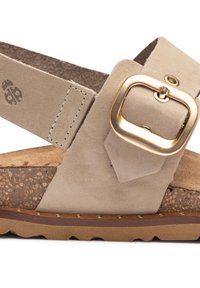 Sandalia de ante beige con una correa ancha, hebilla de metal dorado, plantilla de corcho y suela de goma texturizada marrón. Detalle de costura visible en las correas.