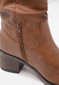 Boon faux leather polvisankalooni, jossa on sivujatkos, paksu korko ja tekstitasoinen pinta. Ominaisuuksiin kuuluu sileä ommel ja muotoiltu design.
