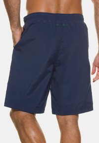 Marineblaue Schwimmshorts aus leichtem, glattem Material mit elastischem Bund und zwei grünen Ösen auf der Rückseite zur Belüftung.