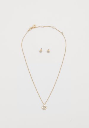 Collana in tono oro con un pendente circolare caratterizzato da un design intagliato e piccole pietre, abbinata a orecchini a bottone coordinati.