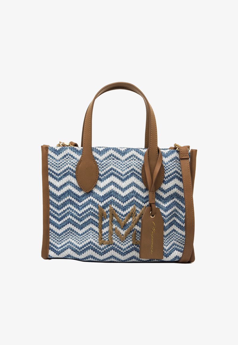 Bolsa tote con un patrón de zigzag en material tejido azul y blanco; detalles y asas de cuero marrón; herrajes metálicos y una etiqueta con el nombre.