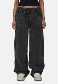 Czarne dżinsy o szerokich nogawkach z wyblakłym wzorem, wysoki stan oraz widoczne szwy. Posiadają dwa guziki oraz teksturę kamienno-wyblakłą.