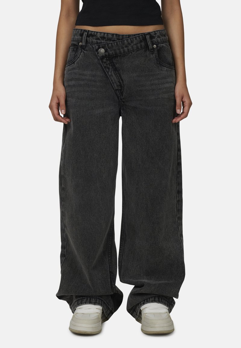 Czarne dżinsy o szerokich nogawkach z wyblakłym wzorem, wysoki stan oraz widoczne szwy. Posiadają dwa guziki oraz teksturę kamienno-wyblakłą.